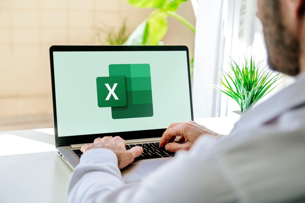 Auf einem Schreibtisch steht ein aufgeklappter Laptop, der gerade Excel öffnet 