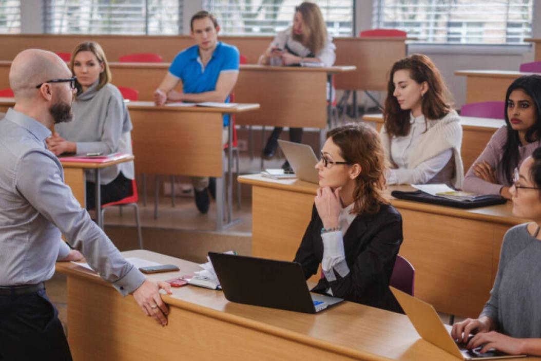 Mann steht in einem Hörsaal vor Studierenden