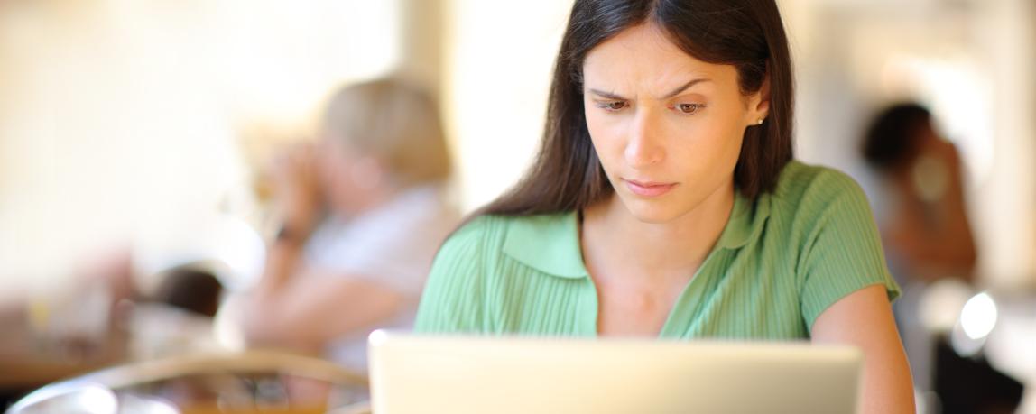 Eine Dame schaut spektisch auf ihren Laptop