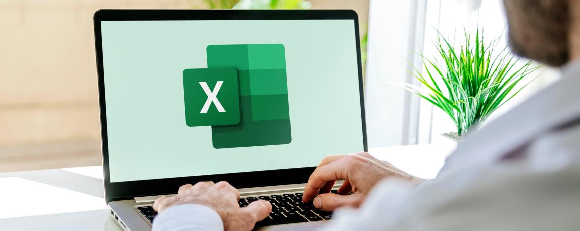 Auf einem Schreibtisch steht ein aufgeklappter Laptop, der gerade Excel öffnet 