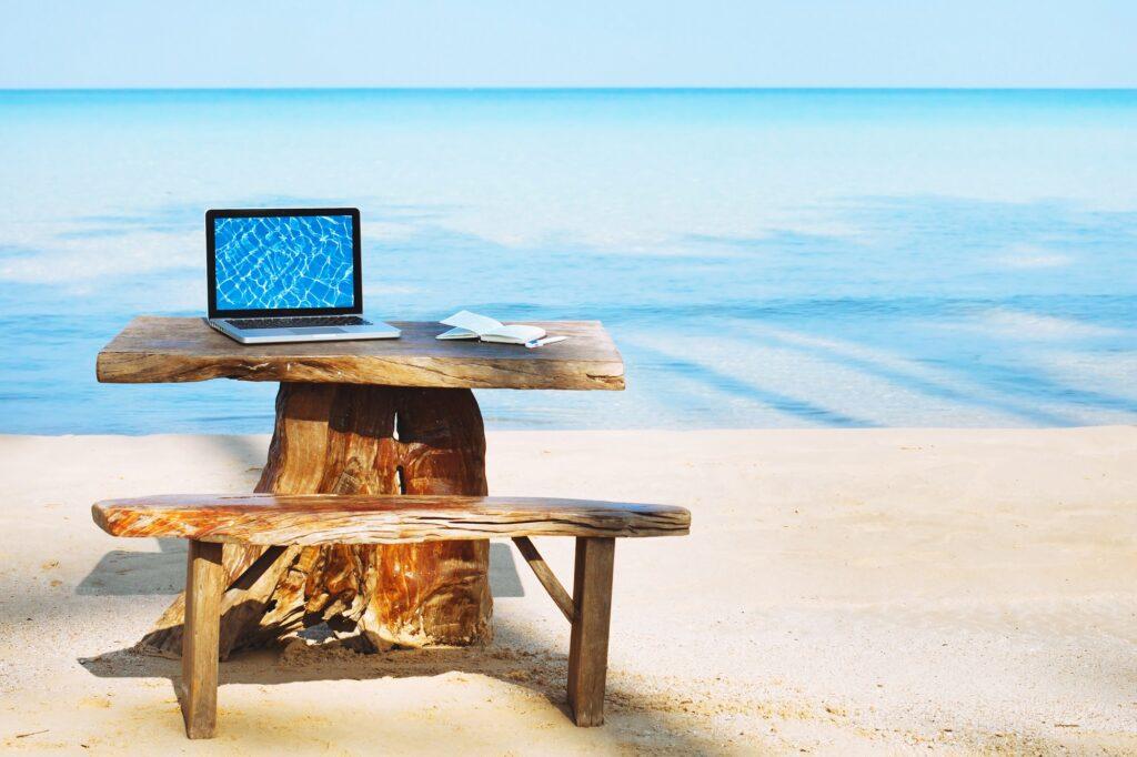 Laptop auf Holztisch am Strand 